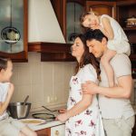 A joyful family moment as parents and children cook together in a cozy kitchen setting.